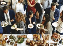 a group of people standing around a table full of food