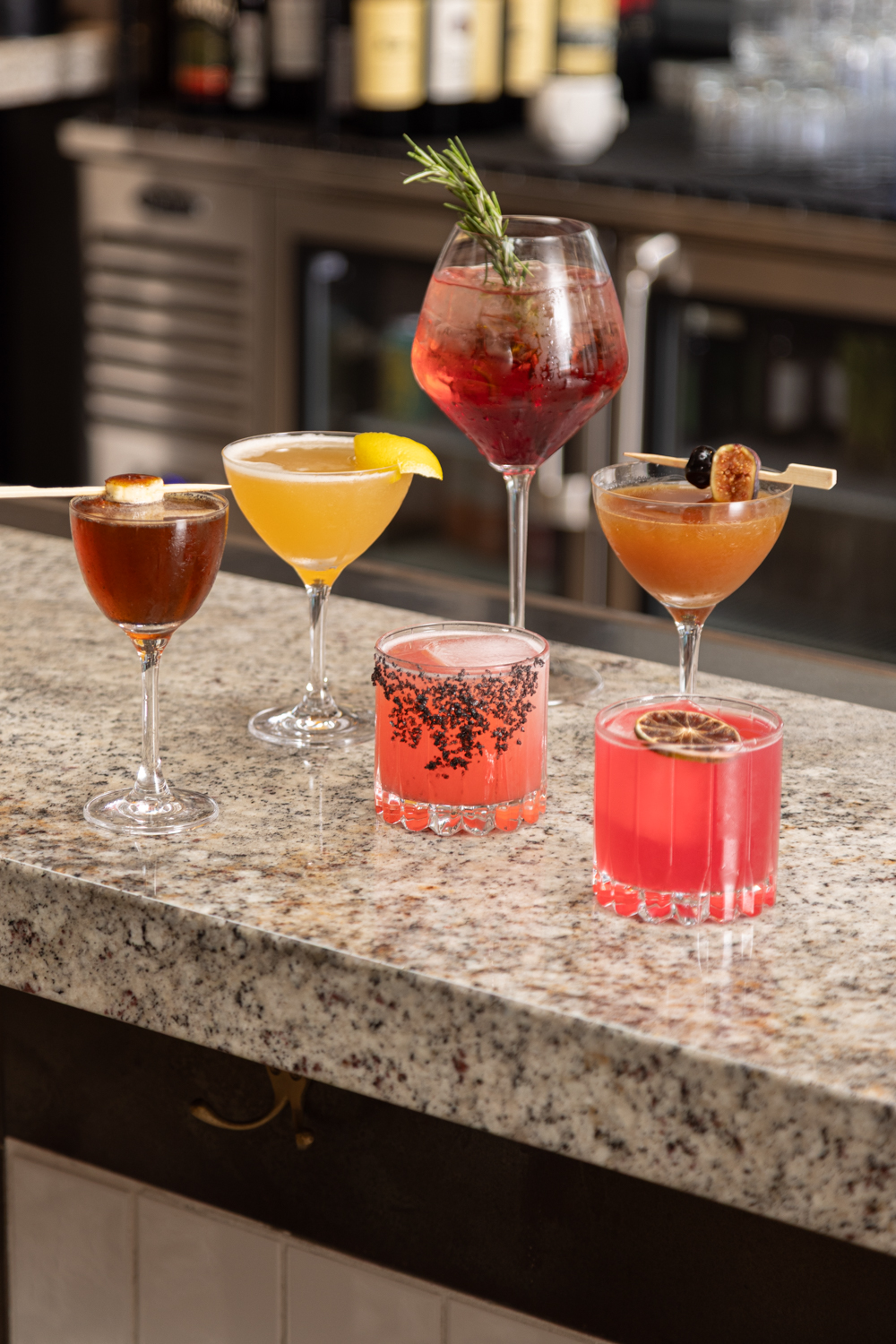 a group of different colored drinks on a counter