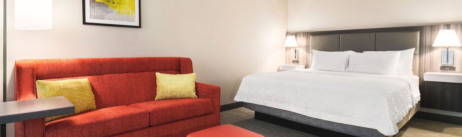 a hotel room with a white bed and red sitting area