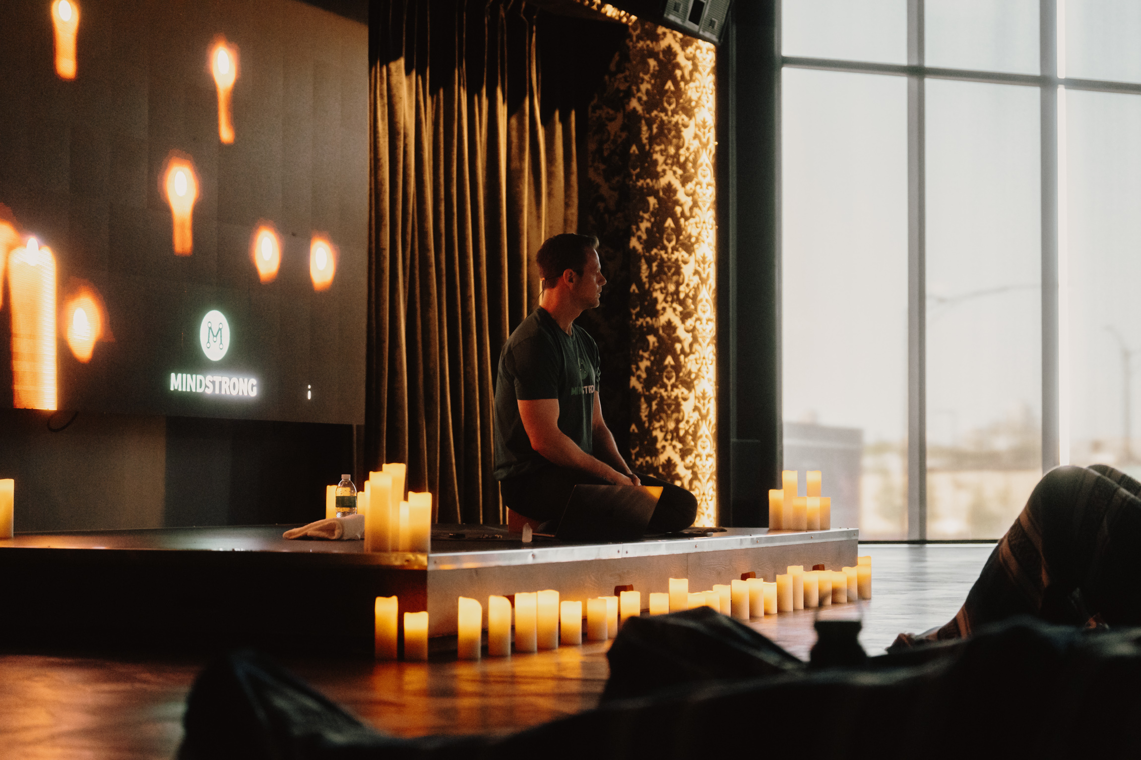 a man sitting on a stage with candles around him