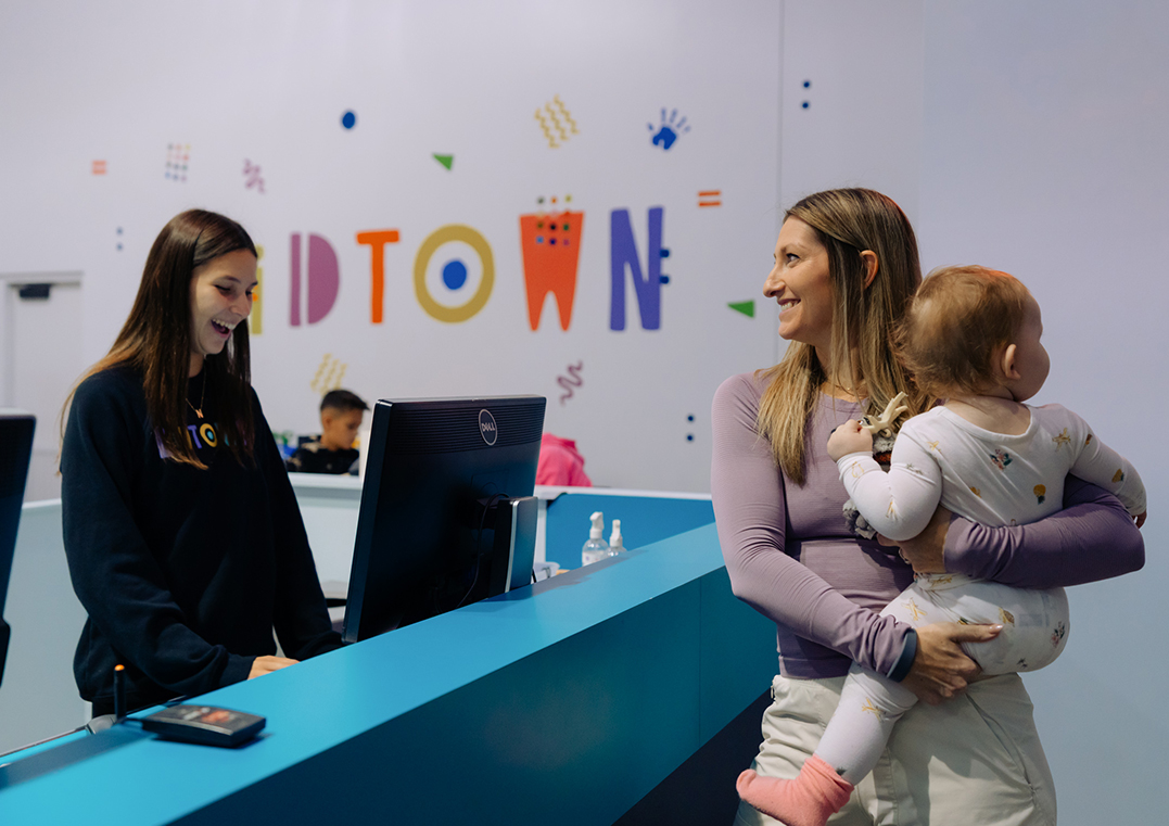 a woman holding a baby and a woman standing behind a counter