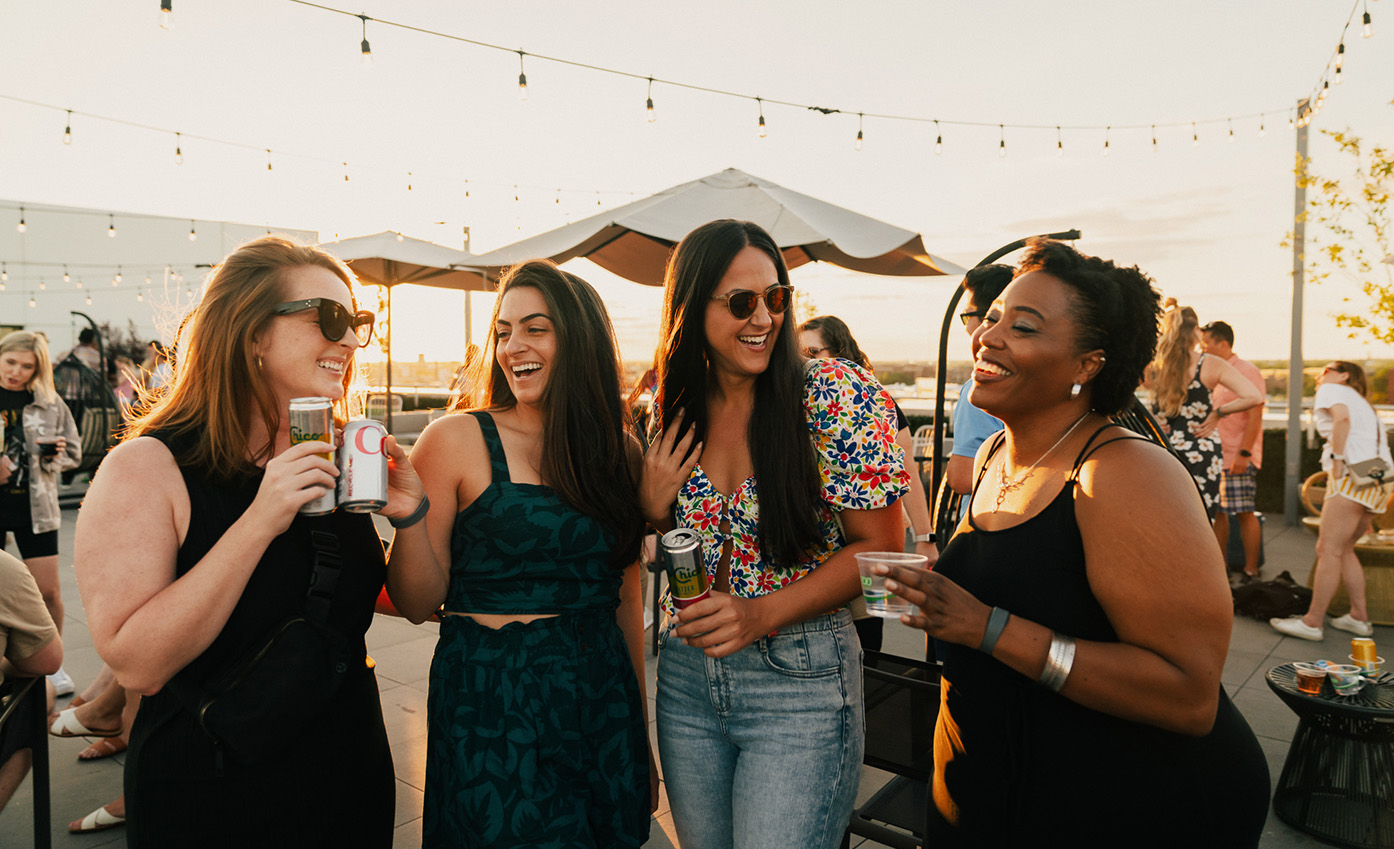 a group of women standing outside holding drinks