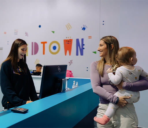 a woman holding a baby and smiling at a desk