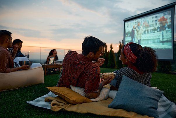 a group of people sitting on a blanket eating popcorn