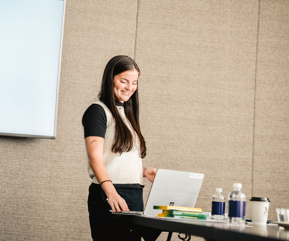 a woman standing in front of a laptop