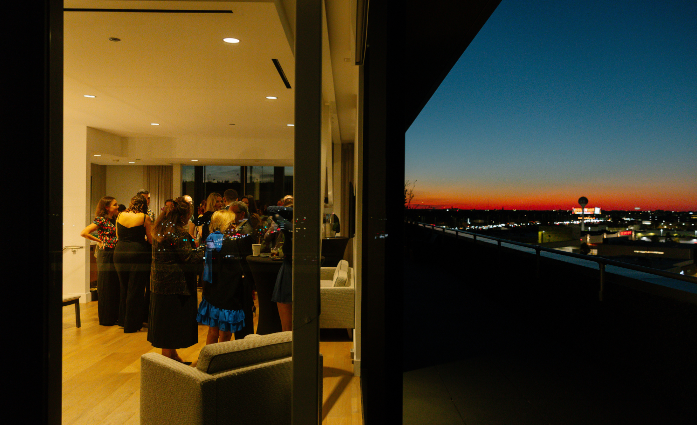 a group of people standing in a room with a view of the sunset