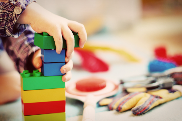 a child's hand holding a stack of colorful blocks