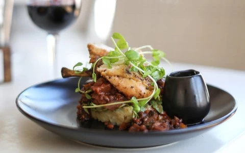 Tasty dish in company of a glass of red wine served in the table