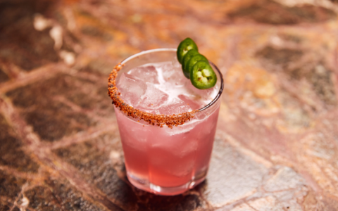 a glass with a drink and jalapeno slices on top