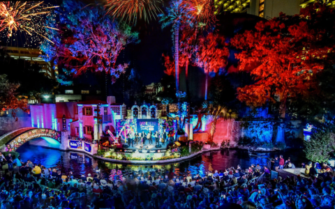 a group of people watching a stage with fireworks in the sky