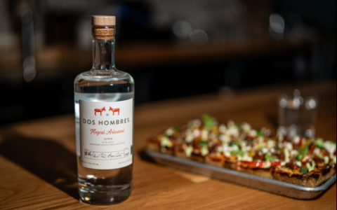 a bottle of alcohol next to a pizza