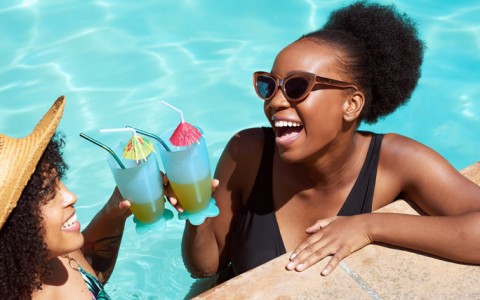 two women in a pool holding drinks