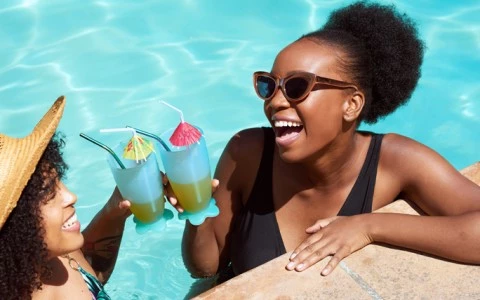 two women in a pool holding drinks