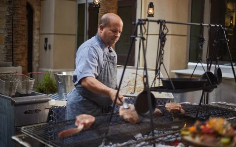 a man cooking meat on a grill