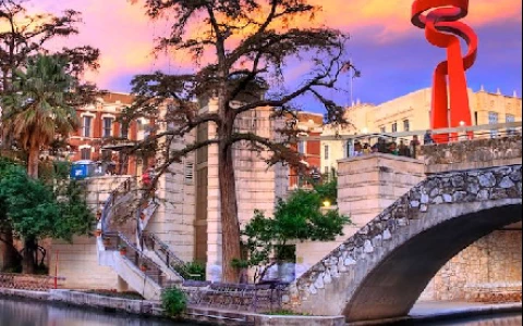 a bridge over a river with a red sculpture