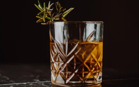 a glass with a drink and a branch of rosemary