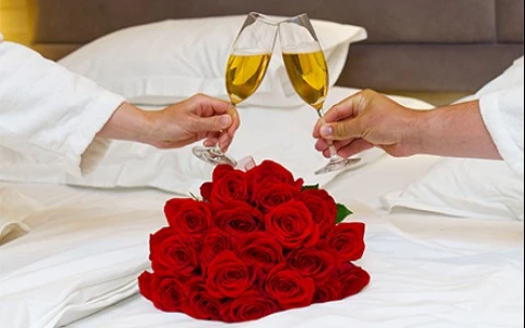 a couple of hands holding wine glasses and a bouquet of roses