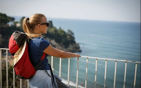 a woman sitting on a railing overlooking the ocean