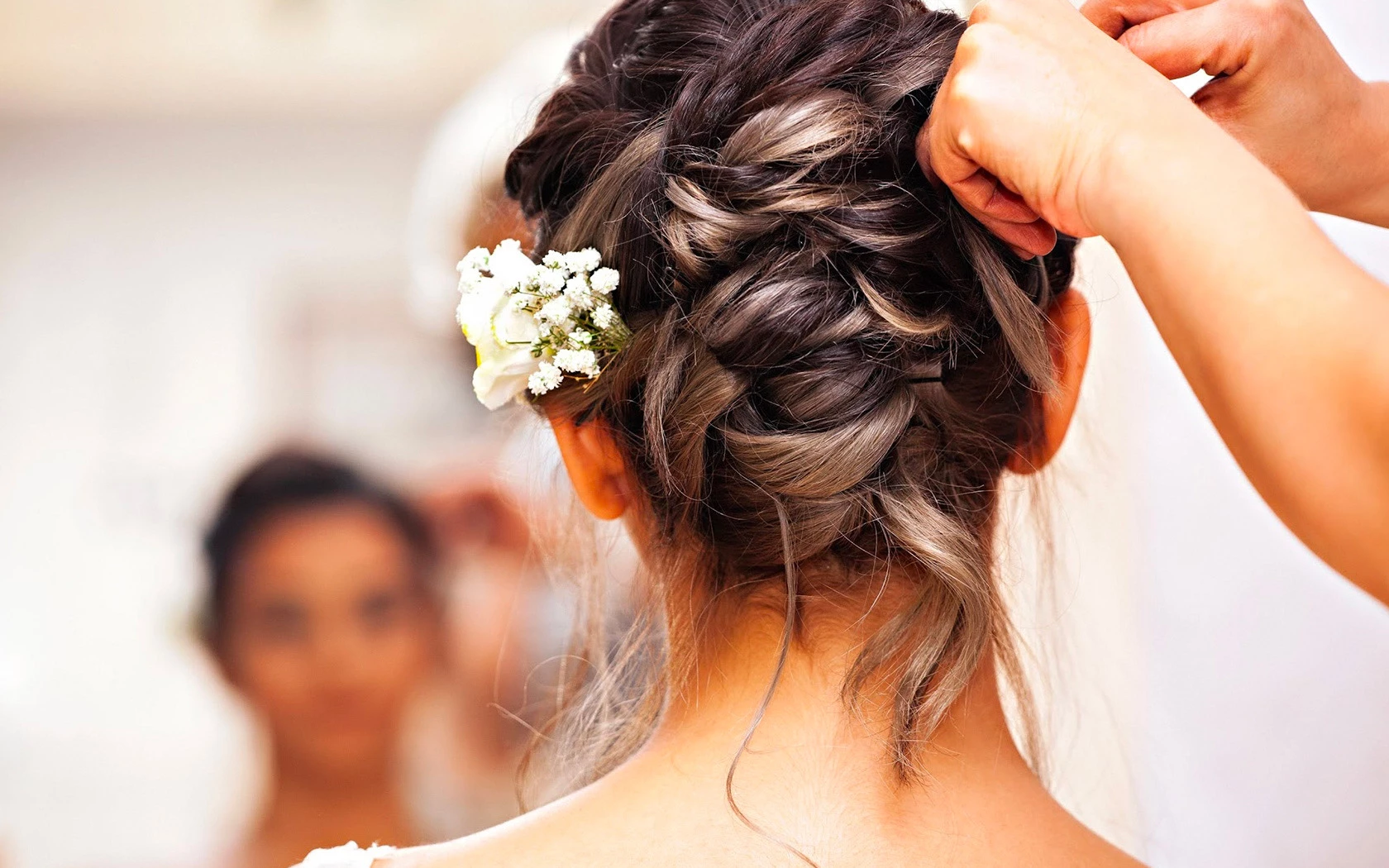 A person finishing up an updo on a bride.