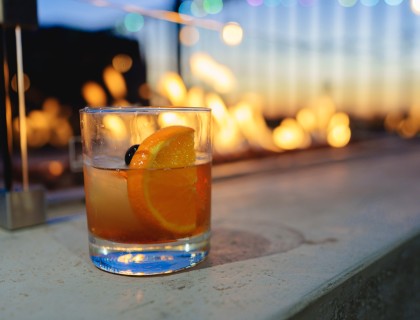 a glass with a drink and a slice of orange on it
