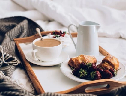 a tray with a cappuccino and a croissant with fruits