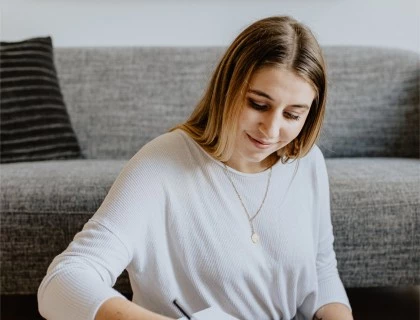 a women sitting at a desk writing