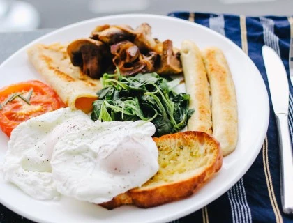 a plate with bread, eggs, greens and tomatoes