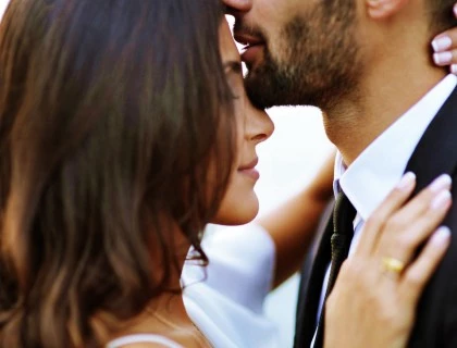a man kissing a woman on her forehead