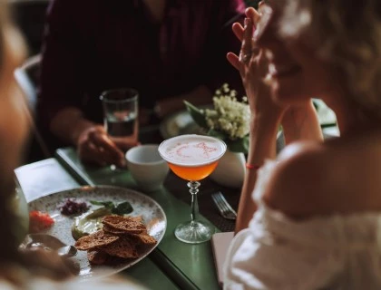 a woman sitting at a table with an organge beverage