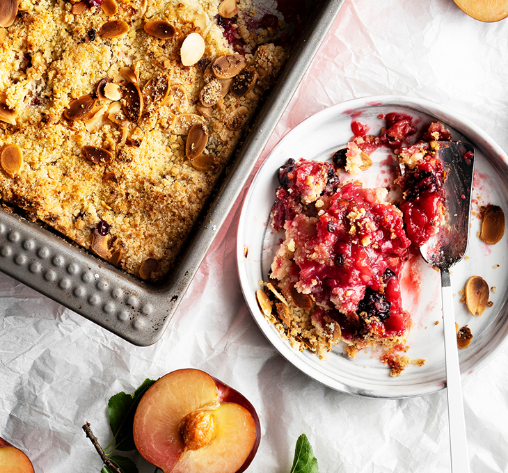 Desserts on table with red berries on top and an apricot on the table