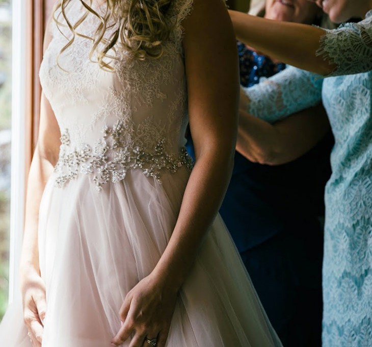 two women helping a bride get dressed