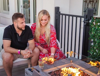 a man and woman sitting on a porch with a table with food
