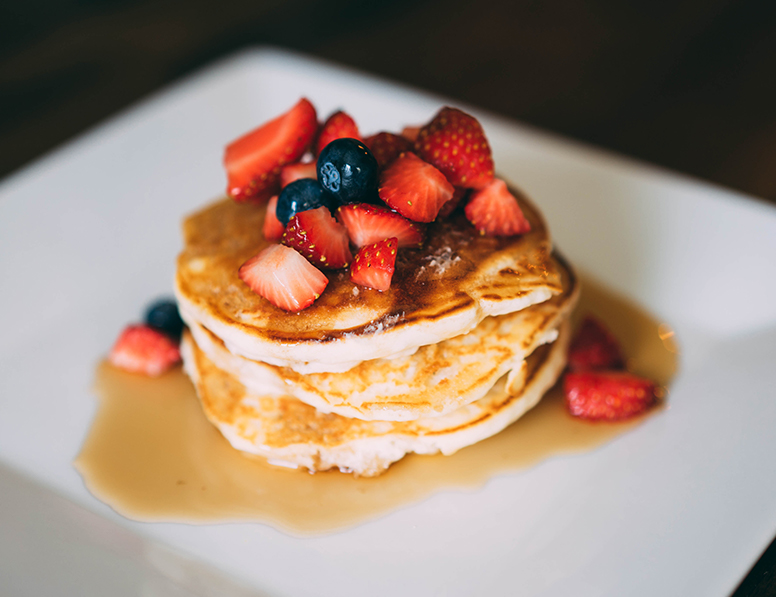 a stack of pancakes topped with strawberries and blueberries