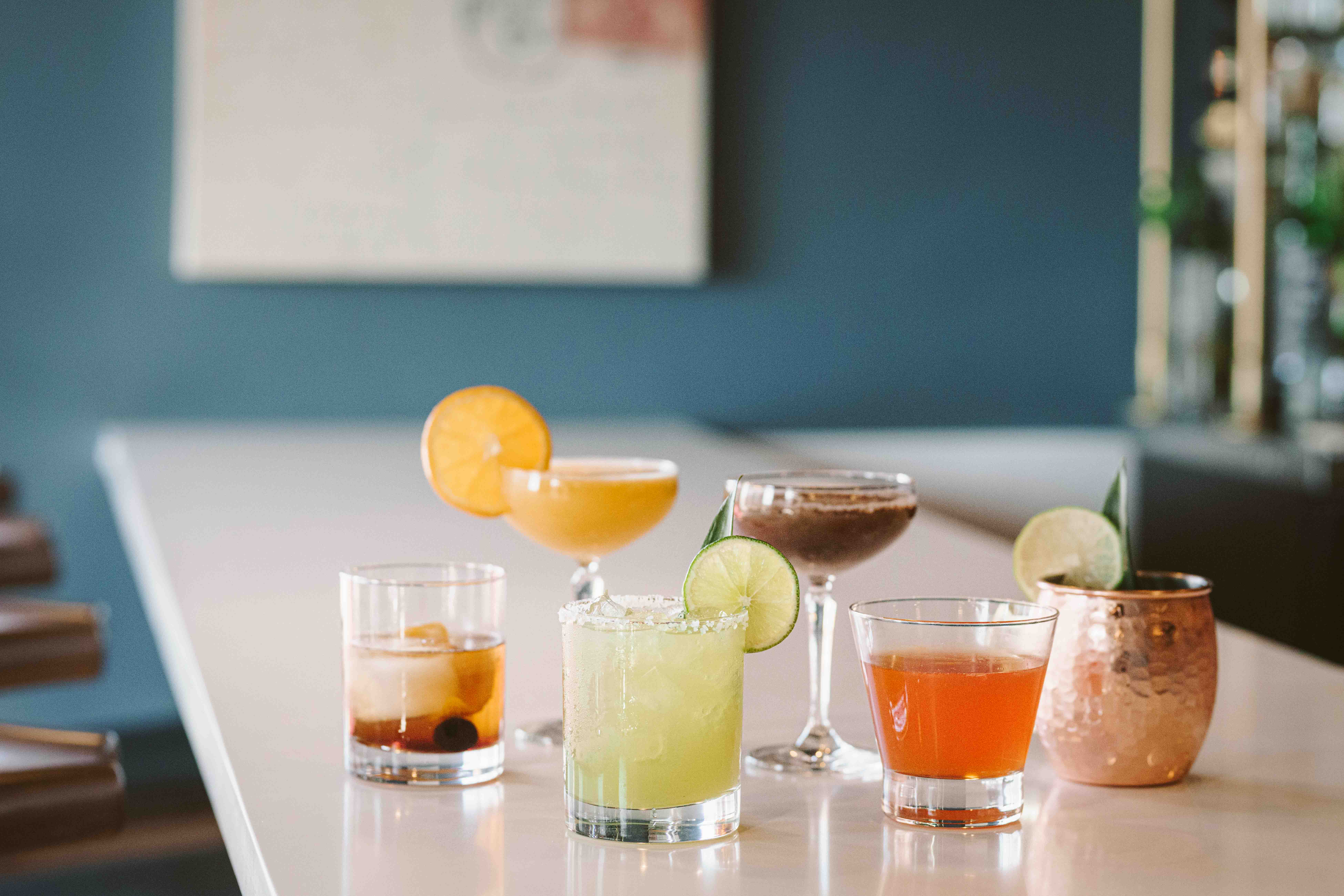 a group of glasses of different colored drinks on a table