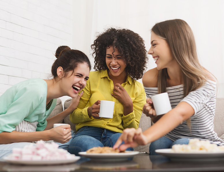 three women smiling drinking out of mugs
