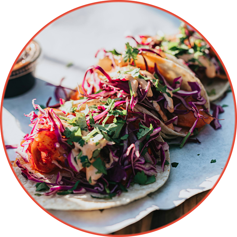 a group of tacos with vegetables and sauce