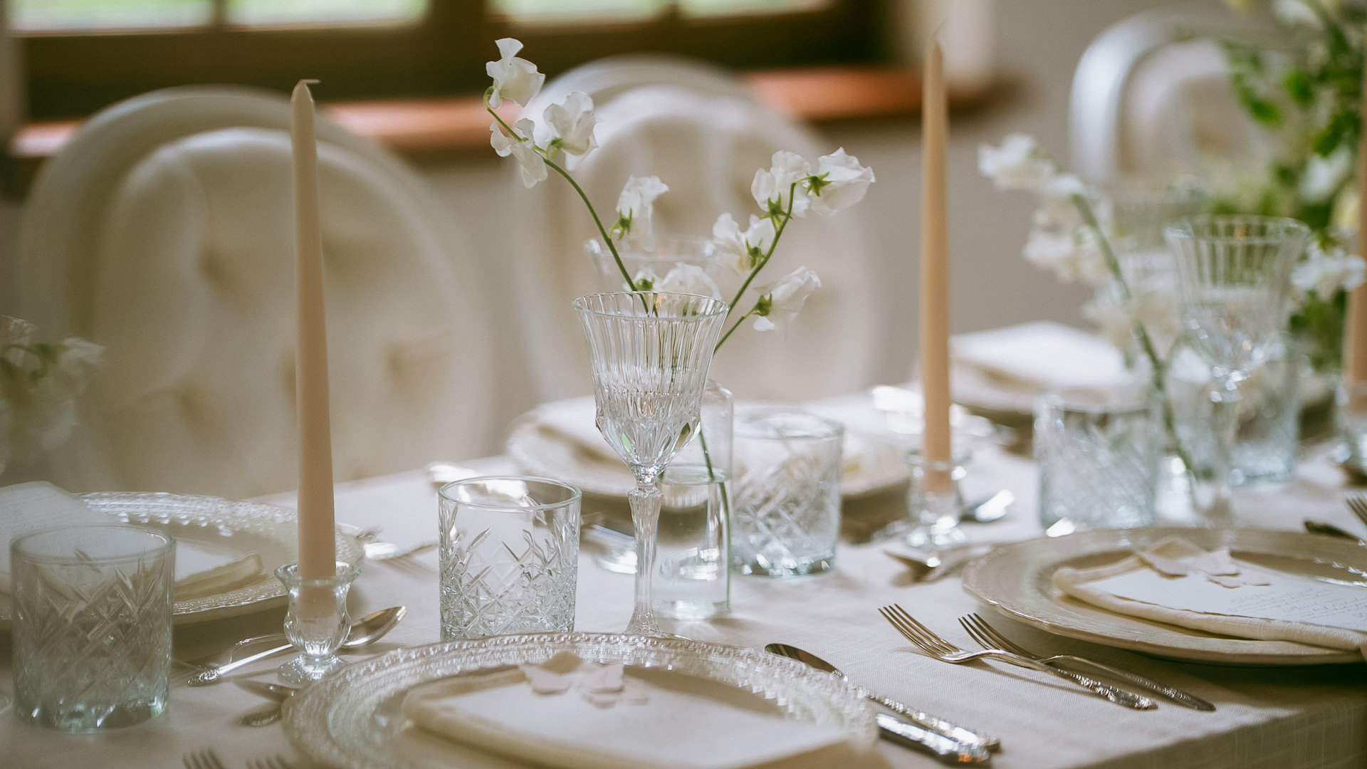 a table set with white flowers and candles