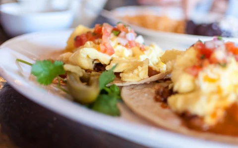 A plate of tacos with scrambled eggs and salsa.