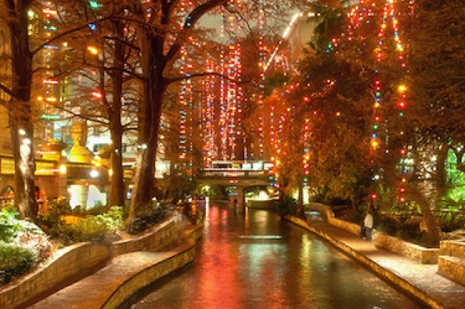 a riverwalk with colorful lights at night