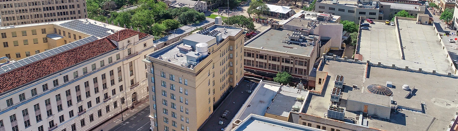 Aerial view of a multi-story building with a flat roof in an urban setting.