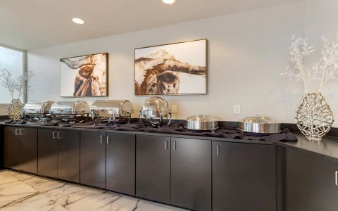 a long buffet with silver warming dishes and black cabinets