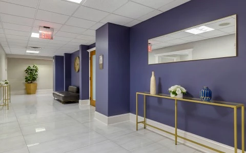 A hotel lobby with a purple accent wall, a gold console table, and a large mirror.