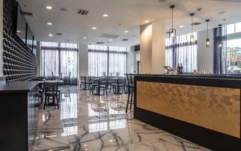 A spacious dining area with a bar, dining tables, and a wine storage wall.