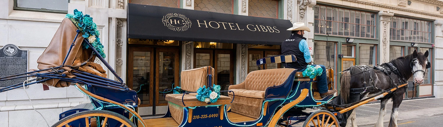 A horse-drawn carriage is parked in front of the Hotel Gibbs entrance under a black awning with the hotel's name.