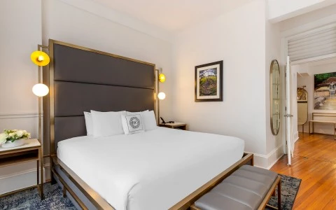 A neatly made hotel room with a large bed, nightstand, and artwork on the wall.