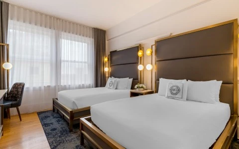 A hotel room with two twin beds, a desk, and a window.