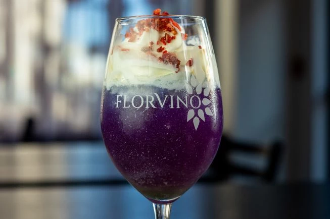 a glass of purple liquid with whipped cream and sprinkles