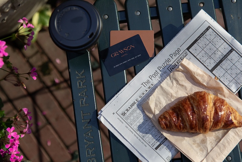 a croissant and newspaper on a bench