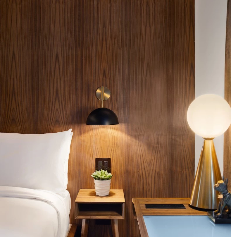 a room with a bed and a table with a lamp on it 