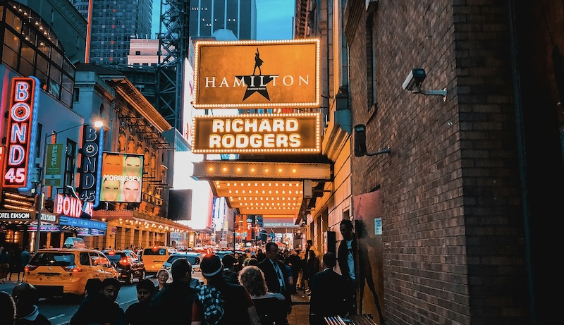 a group of people walking on a sidewalk in front of a building